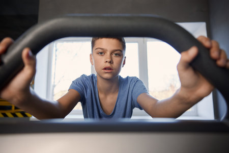 Teenage boy enjoying physical exercise training on mechanical elliptical trainer