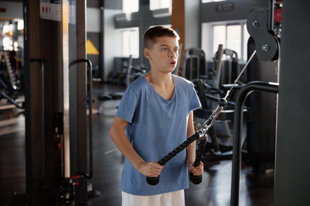 Teenage boy training press at rowing machine at modern fitness centerの写真素材