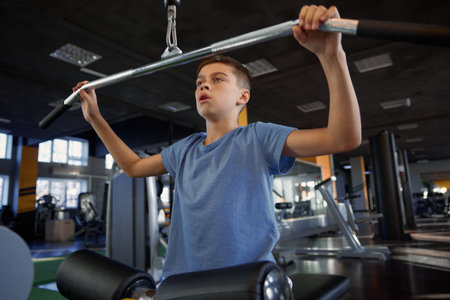 Inspired teenage boy enjoying training on modern gym sports equipmentの写真素材