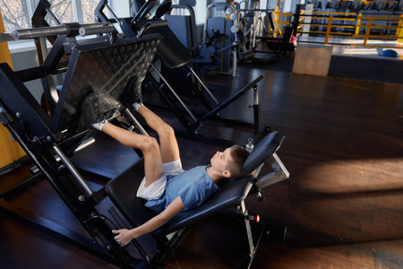 Teenage boy training legs at platform press strength machineの写真素材