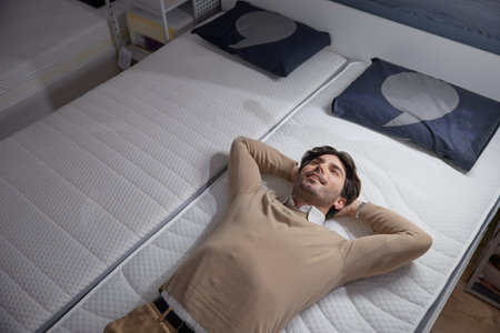 Man checking a stylish mattress visiting a furniture showroom, showcasing ultimate comfortの写真素材