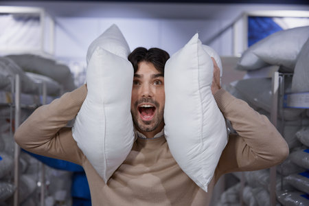 Man surrounded by an array of pillows in the colorful bedding store, smiling happilyの写真素材