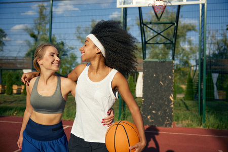 Happy overjoyed young girls friends enjoying time together at basketball courtの写真素材