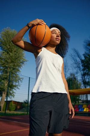 Teenage girl basketball player with ball over outdoor court backgroundの写真素材
