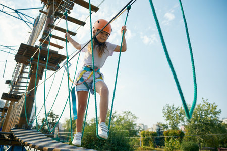 Brave little girl child walking rope ladder moving up on obstacle courseの写真素材