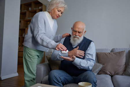 Worried aged woman and old man feeling discomfort in heart area touching chestの写真素材