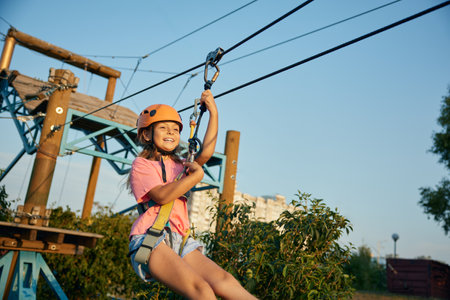 Child girl going down zipline inclined rope with a suspended harnessの写真素材