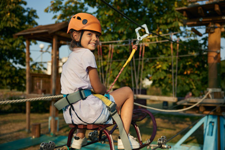 Playful little girl child pulling hawser while overcoming obstacles at rope park
