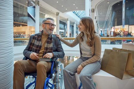 A woman sits nearby a man in a wheelchair at a mallの写真素材