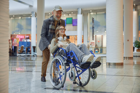 Joyful moments an elderly man gently pushing a young girl in a wheelchair, creating memoriesの写真素材