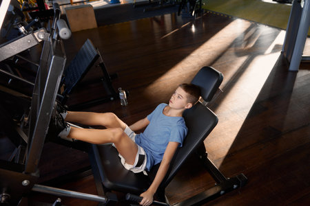 Teenage boy training legs at platform press strength machineの写真素材