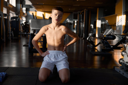 Tired shirtless teenage boy showcasing young trained body after exercise routineの写真素材