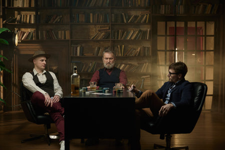 Three distinguished gentlemen playing poker game in a vintage old libraryの写真素材