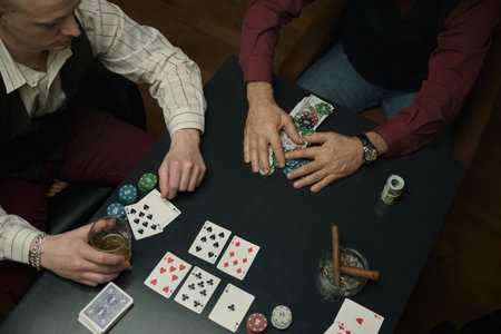 Thrilling moment at poker table with chips, stylish watch, and drink in dimly lit settingの写真素材