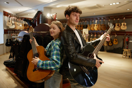 In a music store, a man and a woman are playing their guitars skillfullyの写真素材