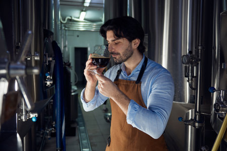 A man is taking a moment to smell a glass of beer in a brewery