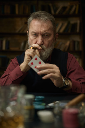 A man lights a cigarette, another man offers assistance, while playing poker