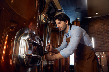 A man wearing an apron is diligently working on a complex machine