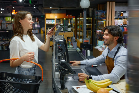 A woman pays for her groceries at the cash registerの写真素材
