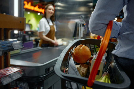 Closeup of man carrying a shopping basket full of groceries to the checkout in a storeの写真素材