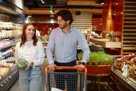 A man and a woman are pushing a cart in a grocery storeの写真素材