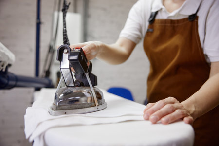 A woman is ironing a freshly laundered white shirt on a boardの写真素材