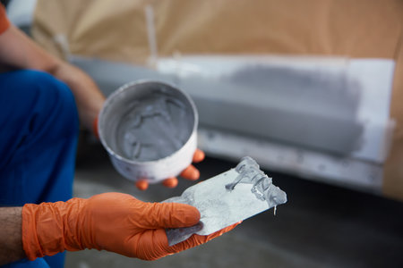 Closeup of technician is meticulously prepping a car panel with primer in a garage workshopの写真素材