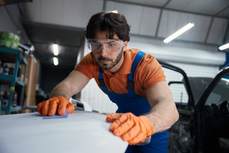 Auto body technician sanding car panel in workshopの写真素材