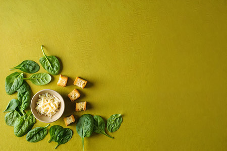 Bowl of fresh spinach salad with cheese and crackers on yellow backgroundの素材
