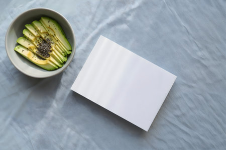 Top view of a plate with sliced avocado and blank card with copy space.の素材