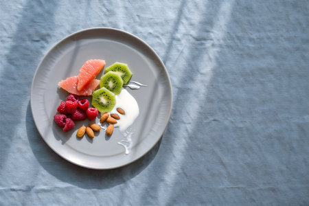 Healthy breakfast with yogurt, fruits and berries on a white plateの素材