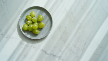 Green grapes on a plate on a white marble background with copy spaceの素材