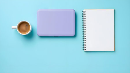 Flat lay of laptop, notepad and coffee cup on blue backgroundの素材