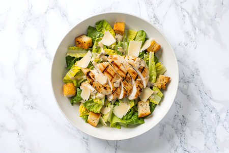 caesar salad with grilled chicken on white marble background - healthy food styleの素材