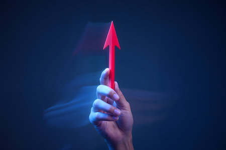 hand holding a red arrow on a dark blue background with copy spaceの素材