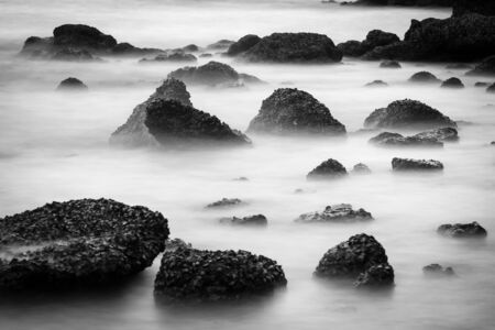 Soft sea wave with long exposure in hard black and white tone background の写真素材