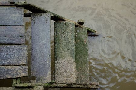 Wet old wooden ladder into the lake while raining.の写真素材