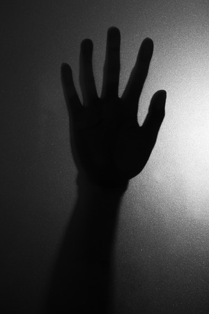 The photograpy of right hand against the window in horror concept close up.(Processed in black and white colour tone)の写真素材