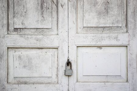 Old wooden door locked by iron lockpad.の写真素材