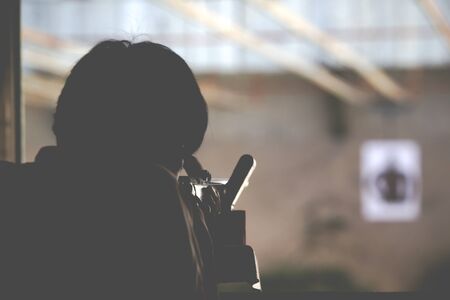 Man is shooting a long rifle to human shooting target.(Processed in vintage colour tone)の写真素材