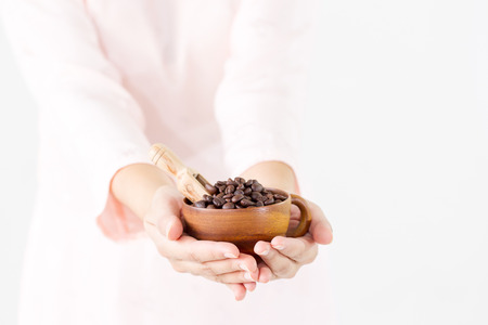 Organic coffee benas in vintage wooden cup on women's hand close up.の写真素材
