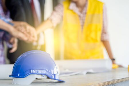 Engineer blue helmet on the table close up with people in the background.の写真素材