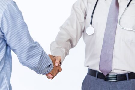 Doctor and man shacking hand on solid white background.の写真素材