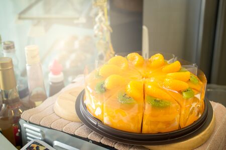 Sliced of orange and kiwi cake on wooden plate close up.の写真素材