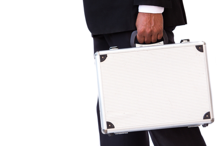 Business man in black suit carrying a hard suitcase on solid white background.の写真素材