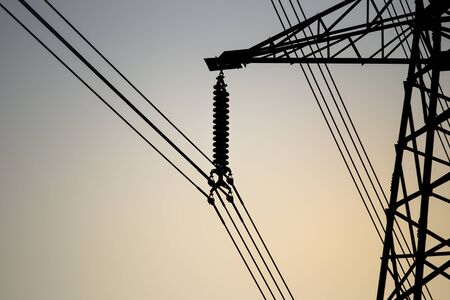 High voltage power tower close up on the worm tone sky before sunset.
