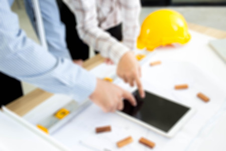 Blured photograph of the professional engineers working together and pointing their fingers to the tablet.  Professional working. for background, backdrop and other use.の写真素材