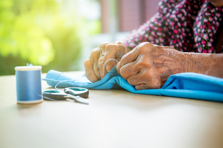 Elder Asian lady age between 80-85 years old is sewing a cloth professionally.の写真素材