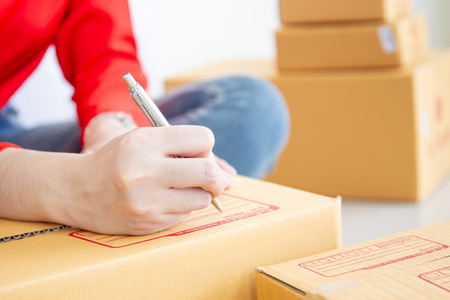Women writing down for the customer address on the parcel box close up.  E-Commerce in modern business style.の写真素材