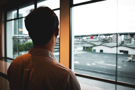 Unidentified Asian man looking out of the window.の写真素材